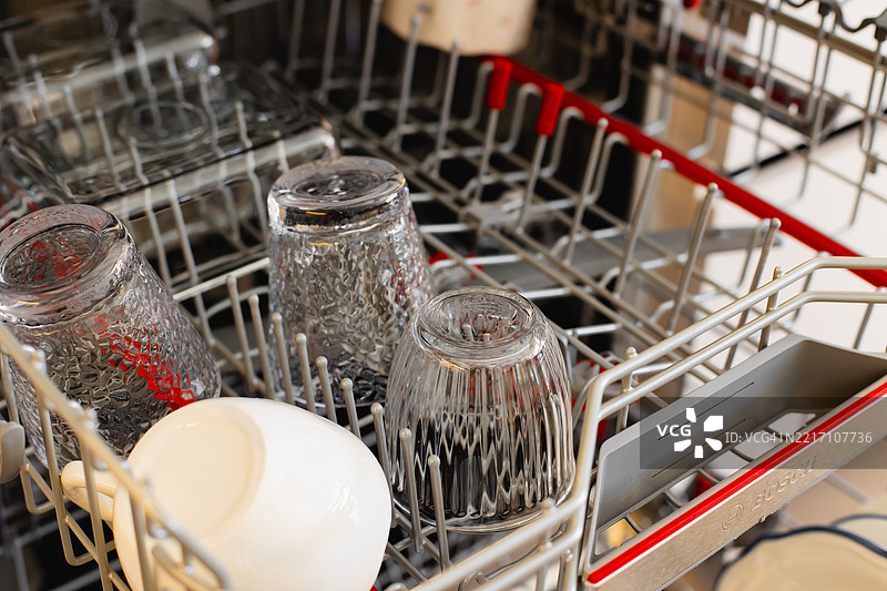打开的洗碗机，内部架子上放着干净的玻璃杯和杯子图片素材