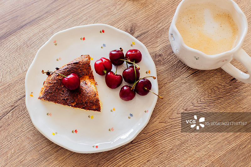 装饰盘上的樱桃蛋糕切片与木桌上的咖啡图片素材