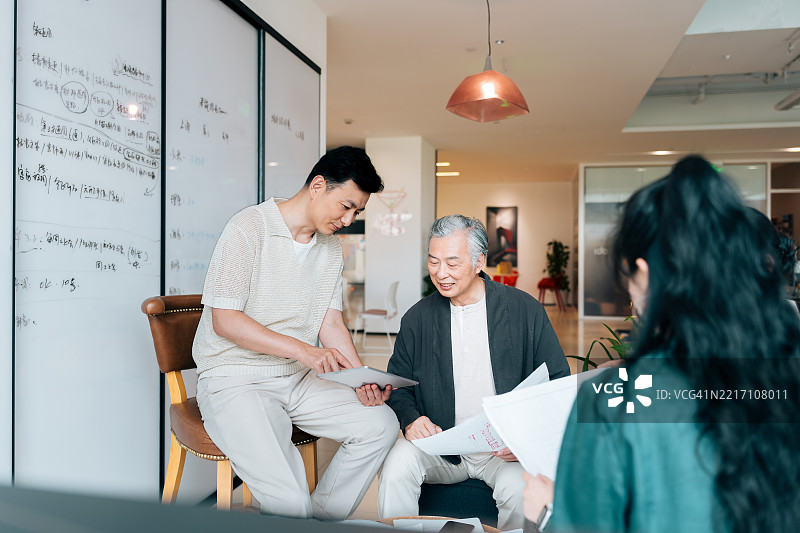 两位商人在现代办公室中合作使用数字平板电脑。图片素材