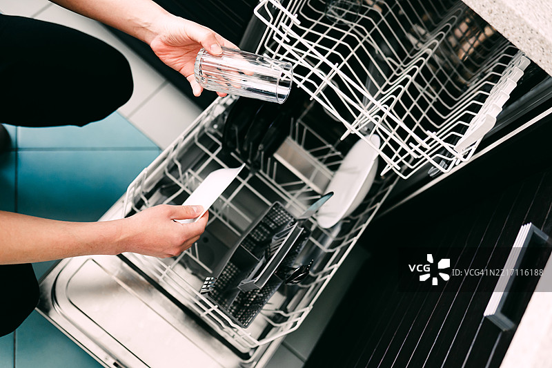 现代厨房环境中一名男子正在装载洗碗机图片素材