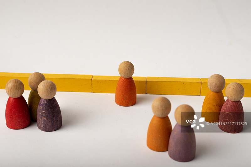 五颜六色的木制插销娃娃被黄色隔板分开图片素材