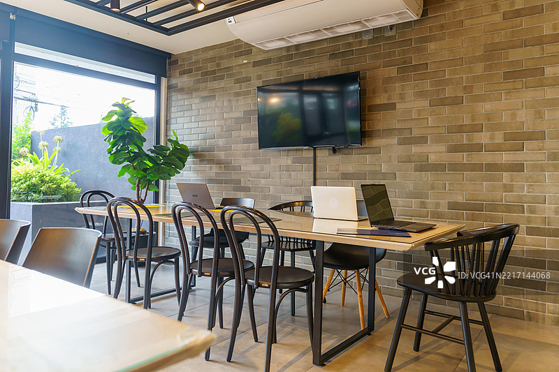 共享办公空间，桌上有笔记本电脑，砖墙上挂着电视屏幕图片素材