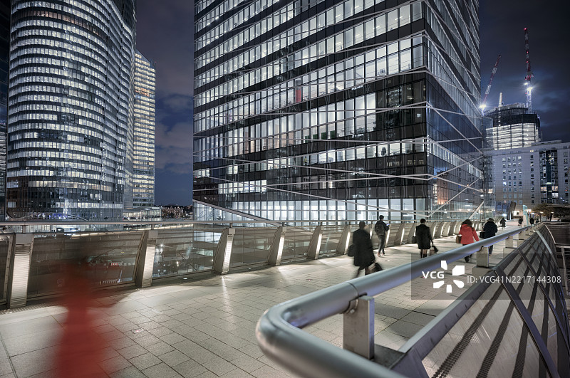 现代商业区的高架人行道上，行人们在傍晚通勤。图片素材