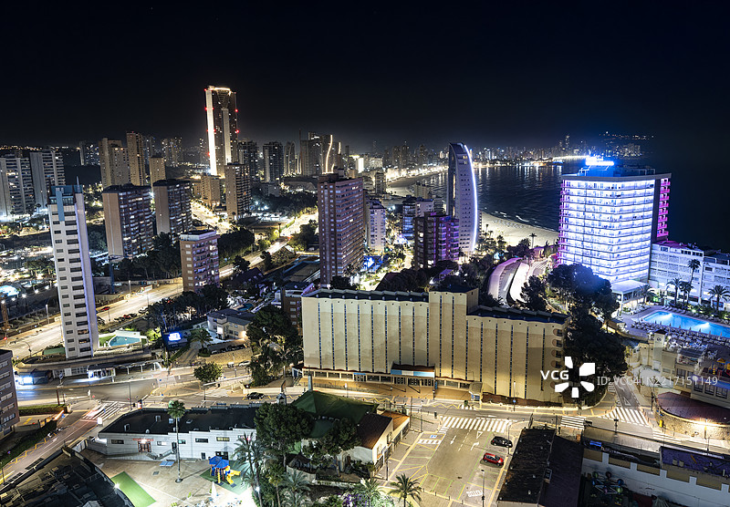 现代城市的高空视角，海边的大型摩天大楼在夜晚灯光下熠熠生辉。图片素材