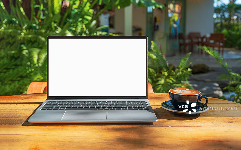 咖啡馆背景下的桌子上放着一台空白屏幕的笔记本电脑。咖啡店模糊背景中的桌子上有一台空白屏幕的笔记本电脑。图片素材