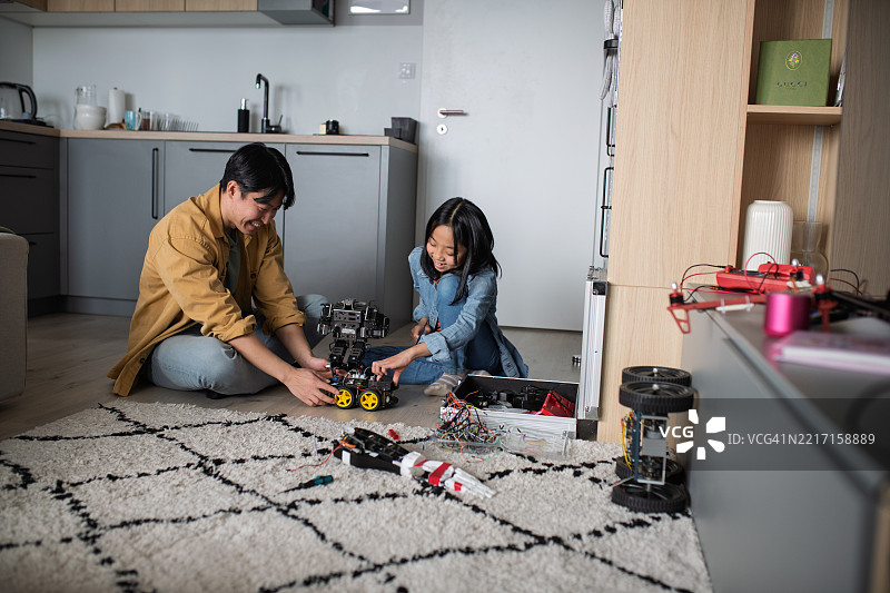 父亲在教女儿关于STEM、机器人技术，并讨论科技。图片素材