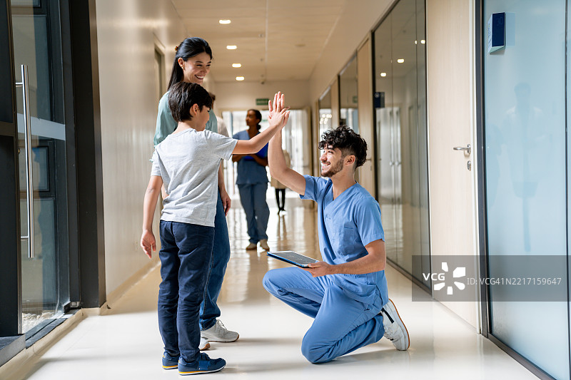 快乐的护士在医院走廊里与孩子击掌。图片素材