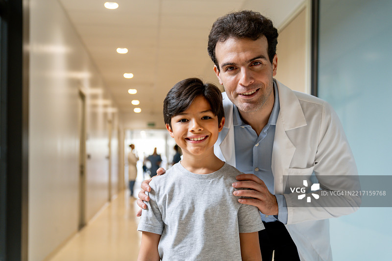 友好的儿科医生在医院里与一个男孩微笑交谈图片素材