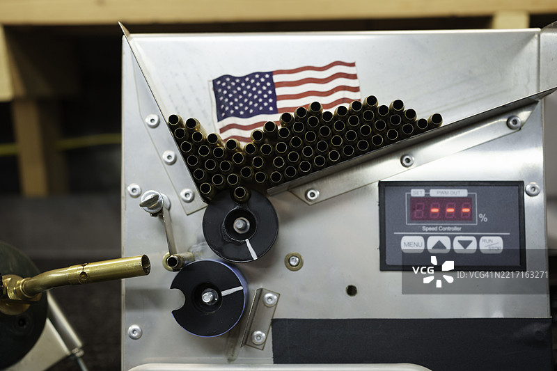 自动化机器将空的黄铜步枪弹药壳送过丙烷火焰喷灯进行退火，以便重新装填和再利用图片素材