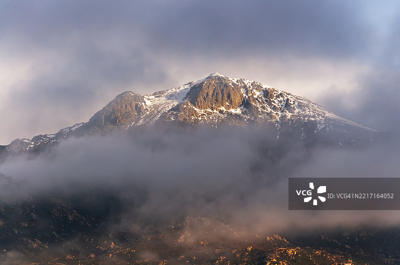 白雪皑皑的山脉上方的蓝天中飘着积云。图片素材