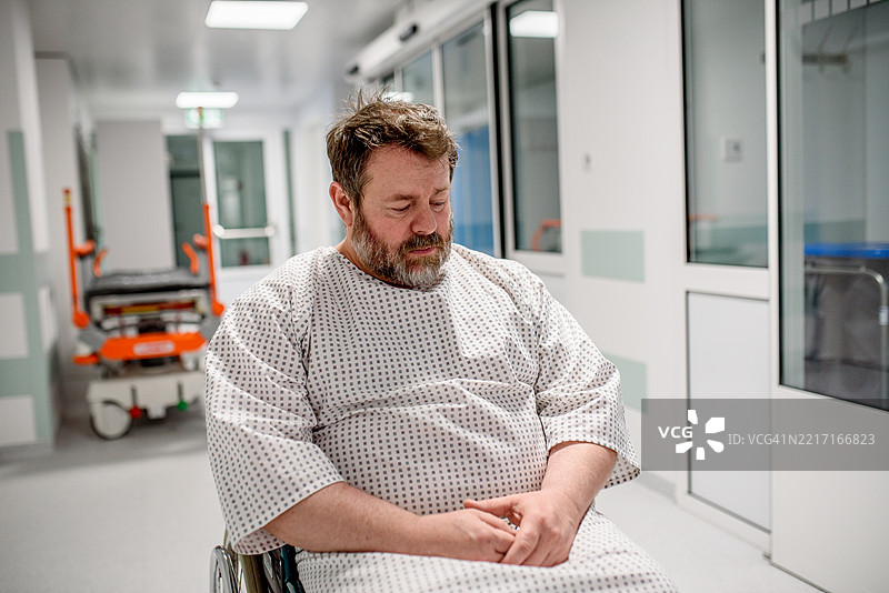 害怕的病人坐在轮椅上，等待在医院走廊。图片素材