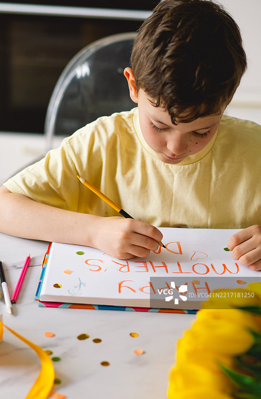 一个男孩认真地制作一张充满真情的母亲节卡片图片素材