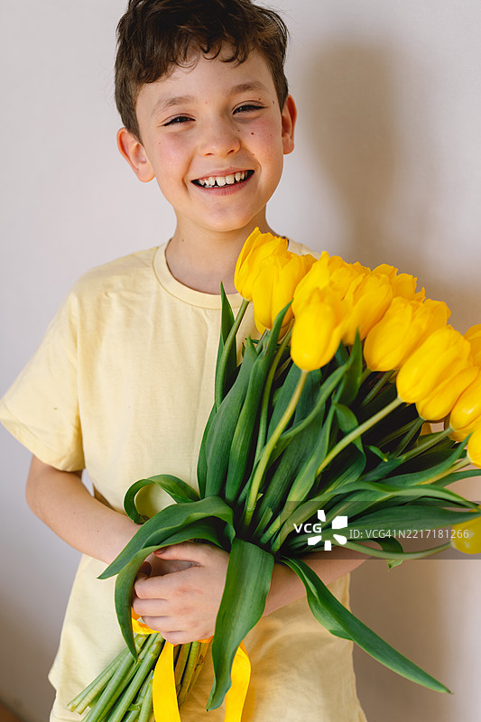孩子快乐地捧着一束鲜艳的黄色郁金香图片素材