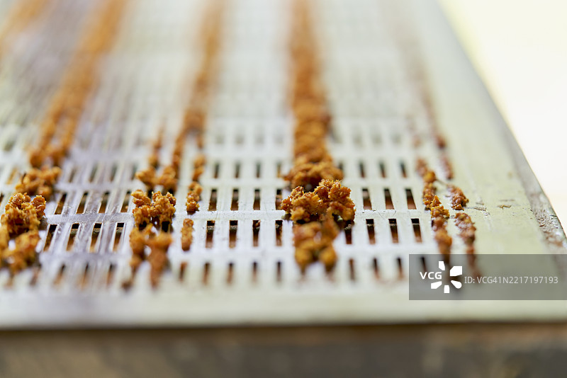 蜂花粉在蜜蜂加工厂的金属网格上晾干图片素材