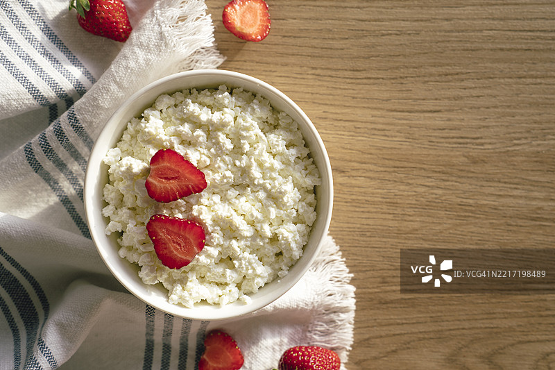 阳光明媚的粉色桌子上放着草莓水果的奶酪。图片素材