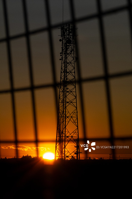 日落时分，围栏后面的通信塔图片素材