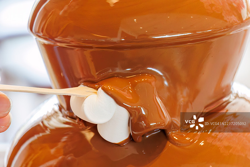 华丽的巧克力喷泉。自助餐厅。许多食物摆放在春季樱花的展示下。图片素材