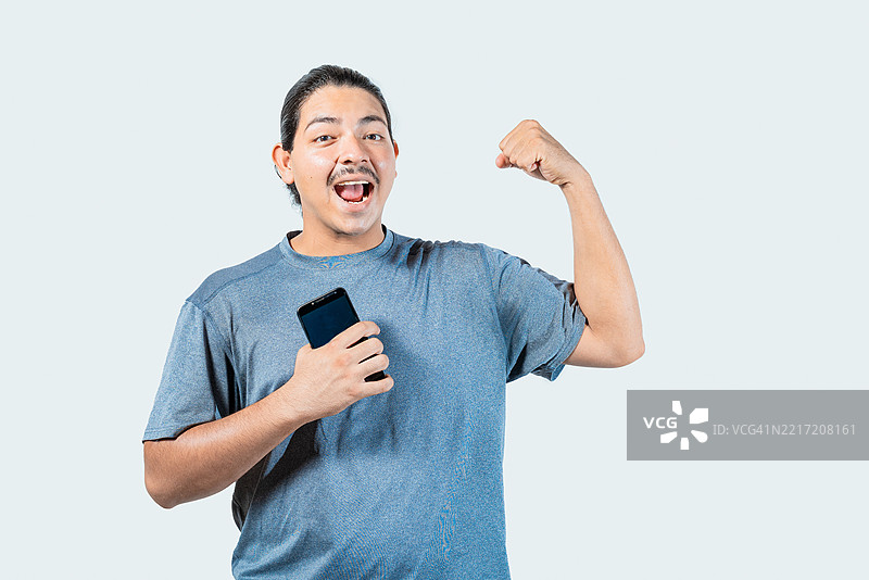 快乐的年轻人手持手机庆祝，孤独的赢家，地点：尼加拉瓜，马那瓜图片素材