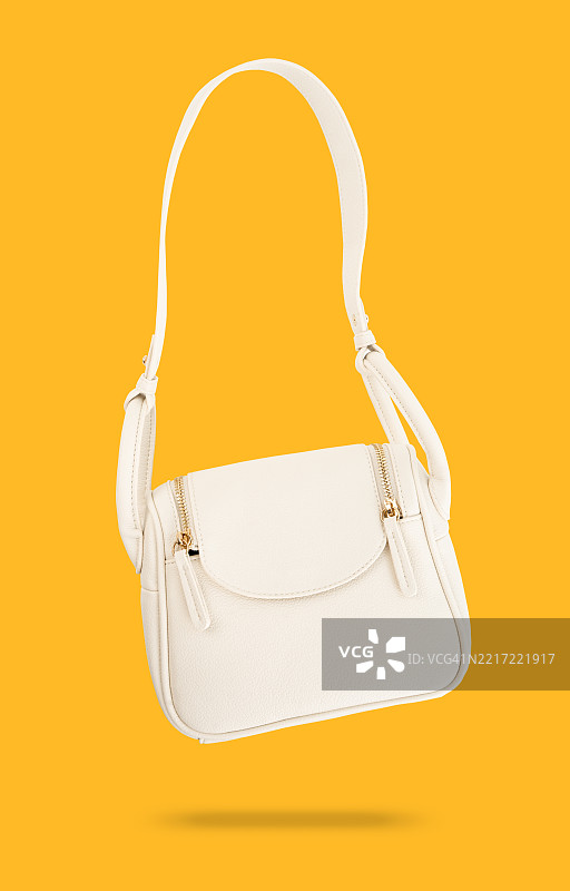 白色皮革女包，孤立在黄色背景上，带有阴影，保存剪切路径。图片素材