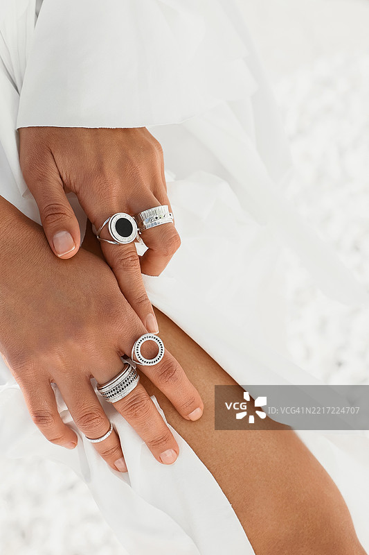 时尚的手指上佩戴着优雅的银戒指，背景为白色。图片素材