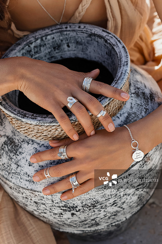 优雅的女性手在艺术环境中展示银戒指和手链图片素材