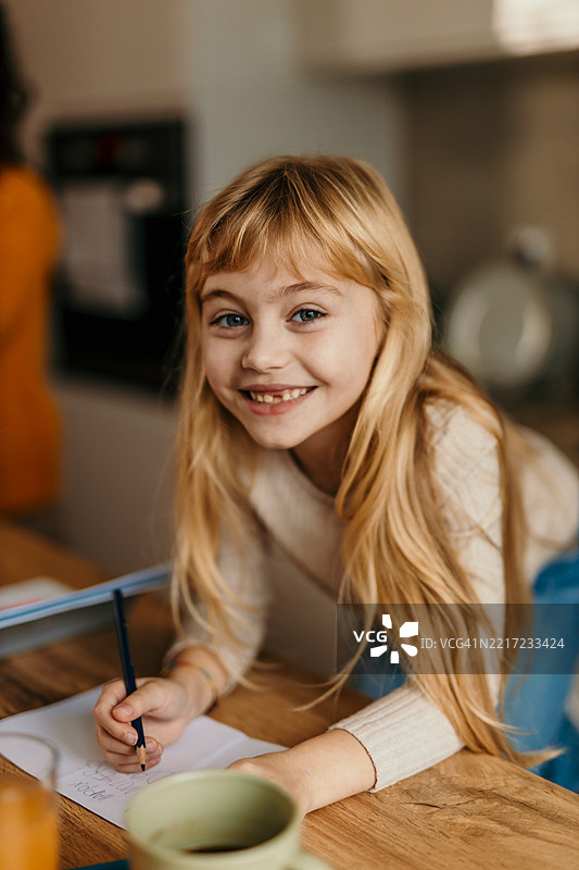 微笑的小女孩在厨房里做作业图片素材