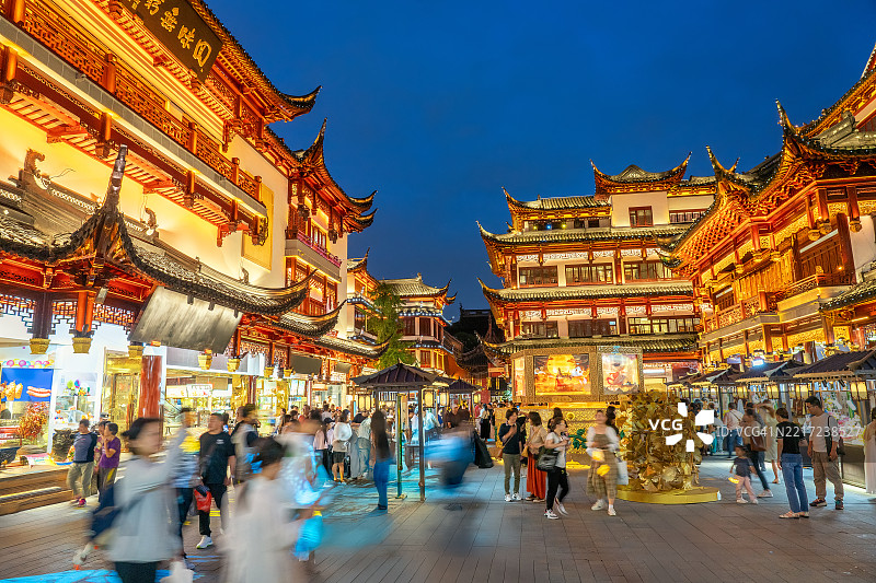 游客们在黄昏时分漫步于上海的豫园，捕捉到传统中国建筑在深蓝色天空下的迷人氛围。中国上海图片素材