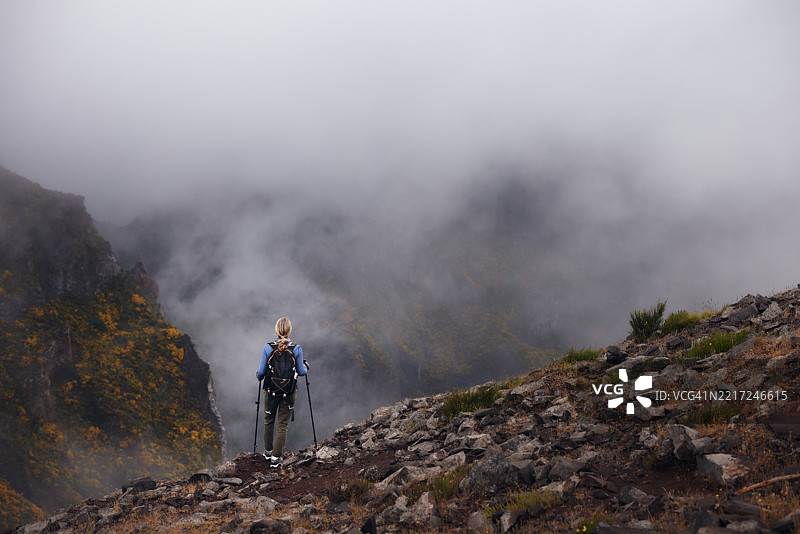 无忧无虑的女性徒步旅行者背对着山脉，欣赏美景。图片素材
