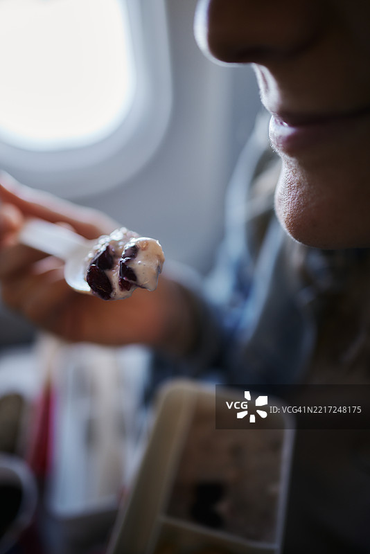 一位女性在飞机上享用零食的特写镜头。图片素材