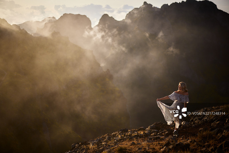 快乐的女人在雾天的山上尽情玩耍。图片素材
