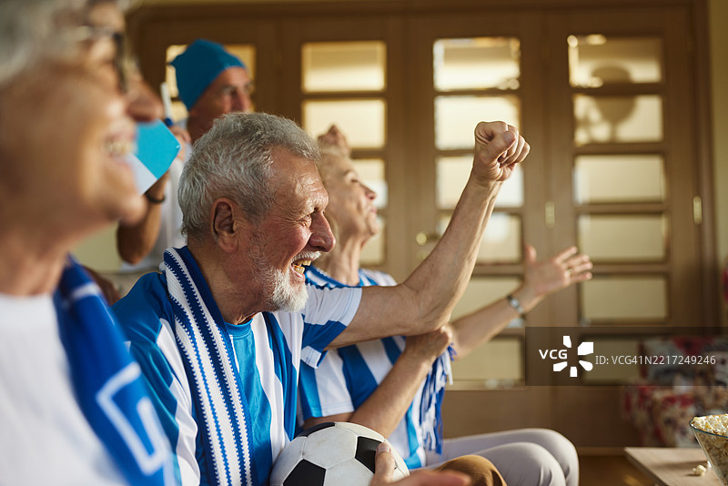 快乐的老年体育迷在养老院观看成功的足球比赛。图片素材