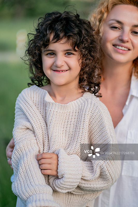 母女俩在花海中骑自行车，享受阳光明媚的一天。图片素材