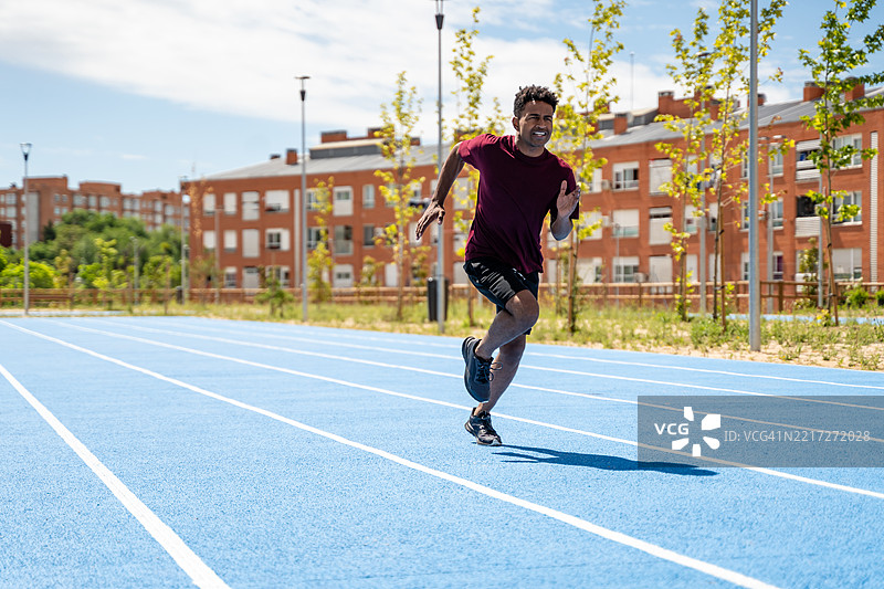 在蓝色跑道上奔跑的成年男子图片素材