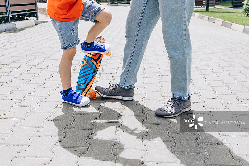 父亲在户外教儿子滑板。家庭亲密关系和积极生活方式的概念图片素材