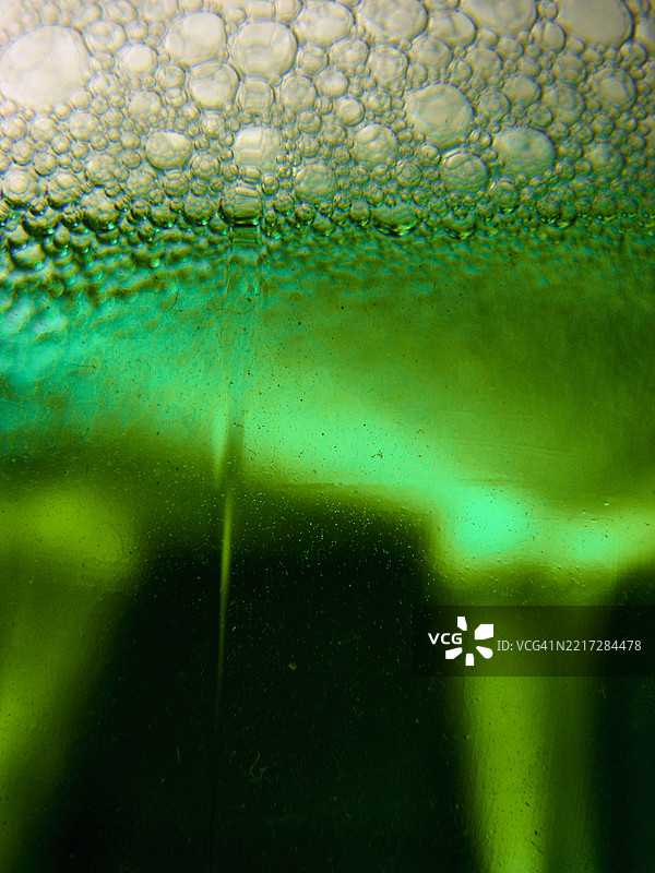 一杯绿色液体的特写，里面紧密地聚集着细小的气泡。图片素材