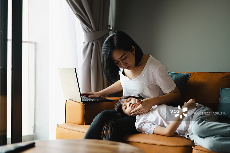 生病的亚洲女孩和母亲在家。图片素材
