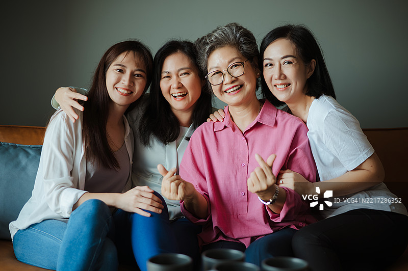 candid family moment: 年长的妈妈和她的女儿们对着镜头微笑。图片素材