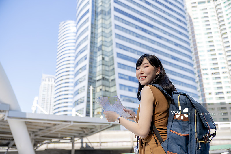 女性游客手持地图和相机探索城市，城市旅行与冒险概念图片素材