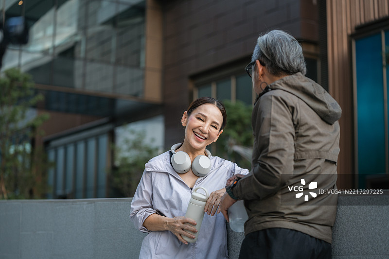 一对老年夫妇在跑步间歇时，边聊天边笑着观看手机上的搞笑视频图片素材