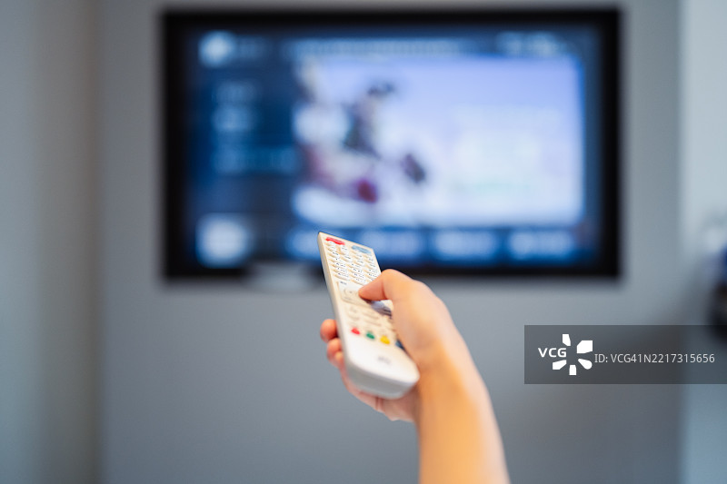 我正在拿着电视遥控器换频道。图片素材