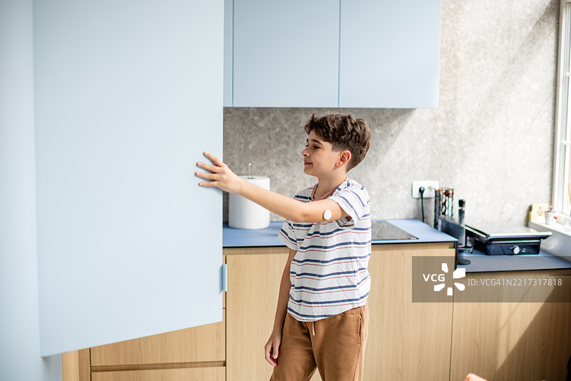 年轻男孩在厨房里检查血糖，管理1型糖尿病。图片素材