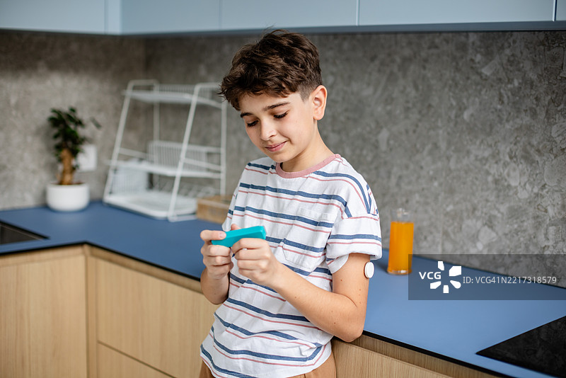 年轻男孩在现代厨房环境中利用科技管理1型糖尿病，享受轻松的下午时光图片素材