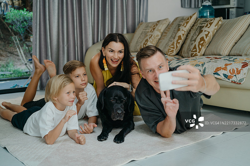 一家有两个男孩和一只狗的家庭在家里拍自拍照图片素材