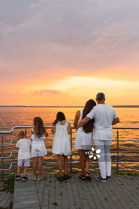 幸福的五口之家站在码头上，俯瞰海洋，享受美景，感受宁静的氛围。图片素材