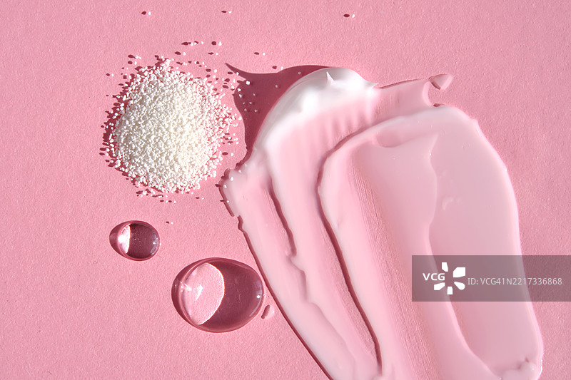 粉色背景上的美容产品，水面反射的光泽图片素材