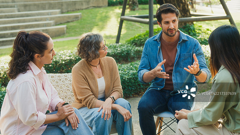 多元化的人群在公园中参与支持性团体治疗会议，分享个人故事和建议，以促进心理健康和康复。心理健康社区概念。图片素材