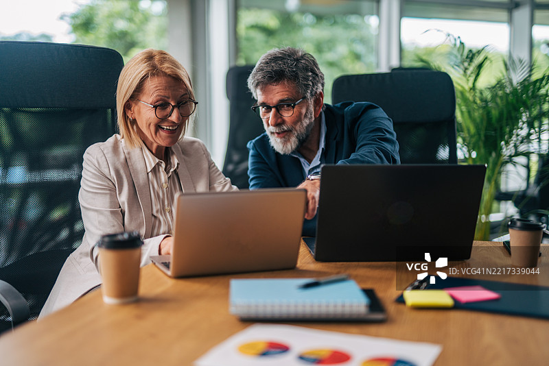 高级商务同事在现代办公室中协作使用笔记本电脑图片素材