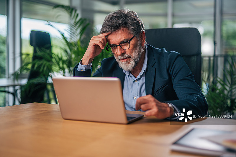 沉思的商人在办公室使用笔记本电脑，遇到问题图片素材