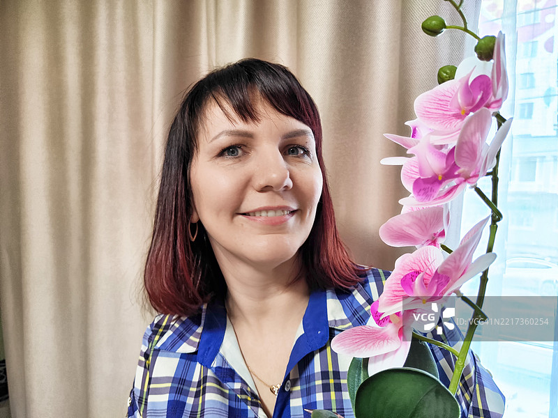 中年女性心理学家在她的办公室微笑，办公室里有花卉装饰图片素材