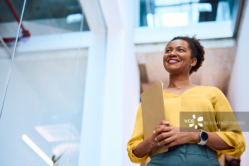 自信的女商人在现代办公室里手持夹板微笑图片素材